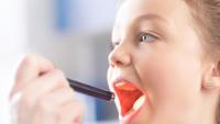 Doctor checking throat of little girl